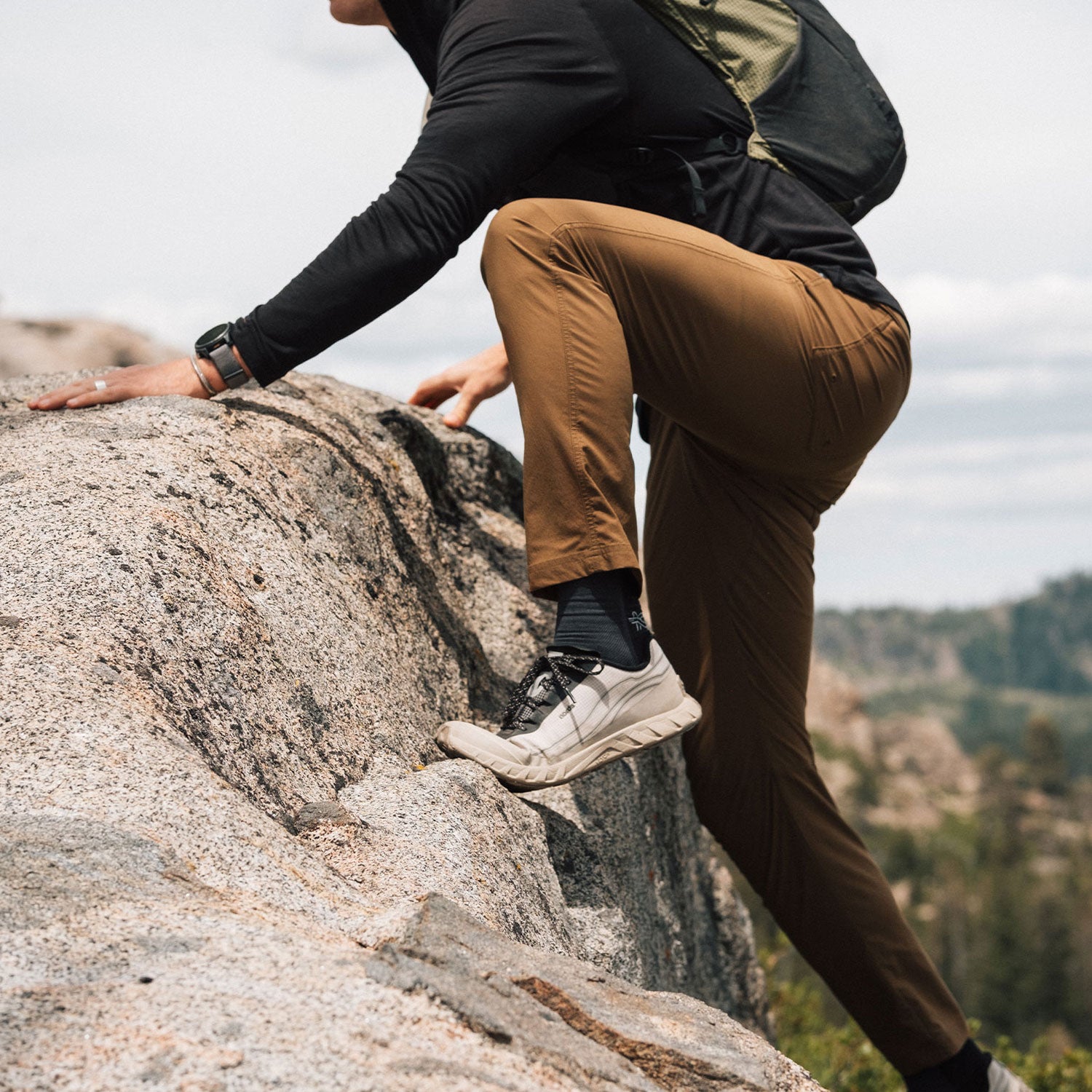 Man scrambling a rock wearing brown stretchy, durable KETL Shenanigan Outdoor pants.